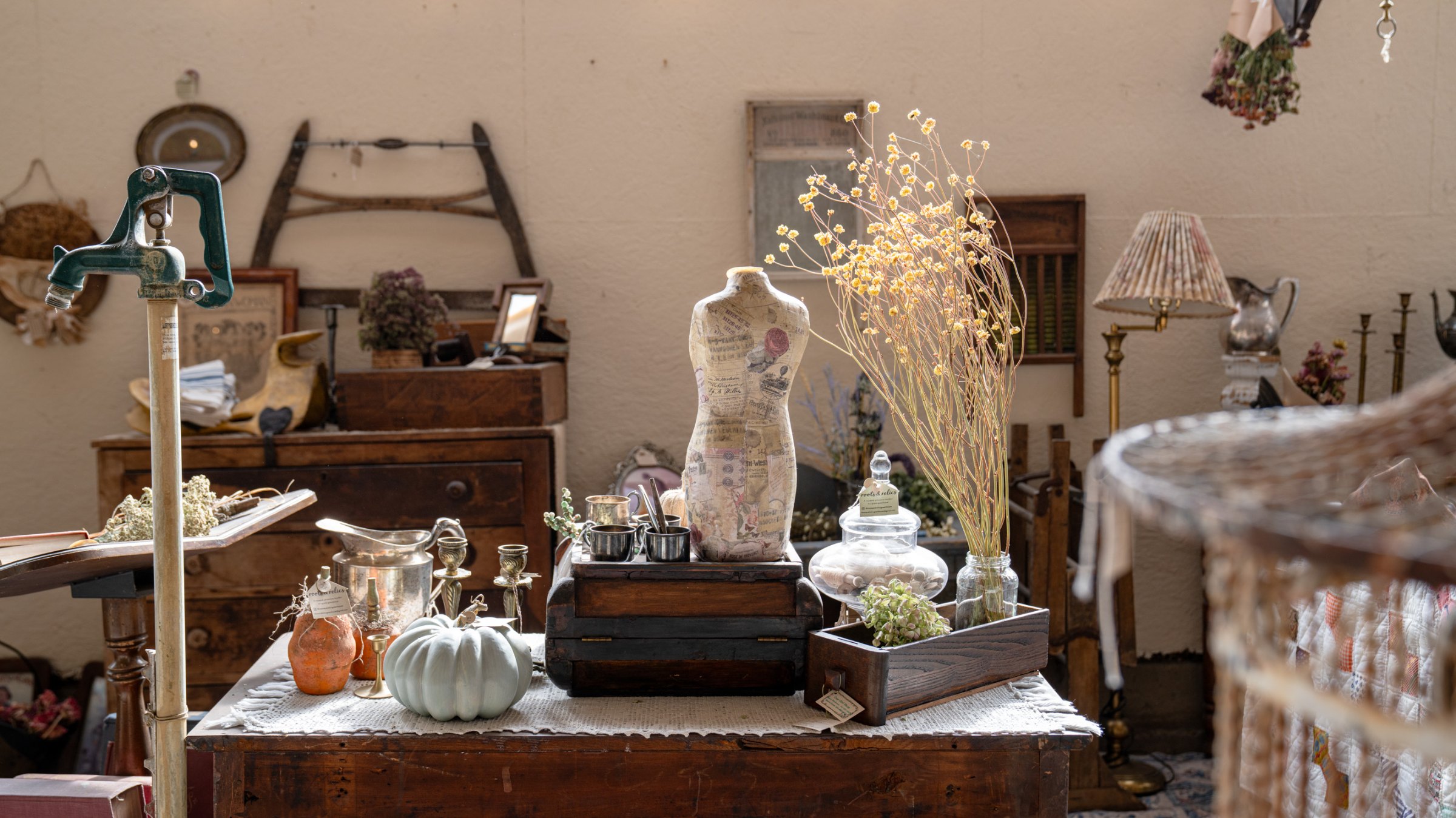 Dress form, vintage luggage, and glassware in an autumn display