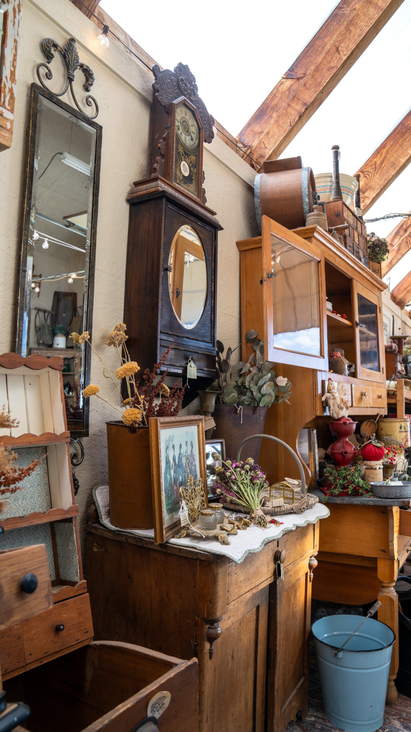 Antique mirrors and wooden furniture along the greenhouse wall