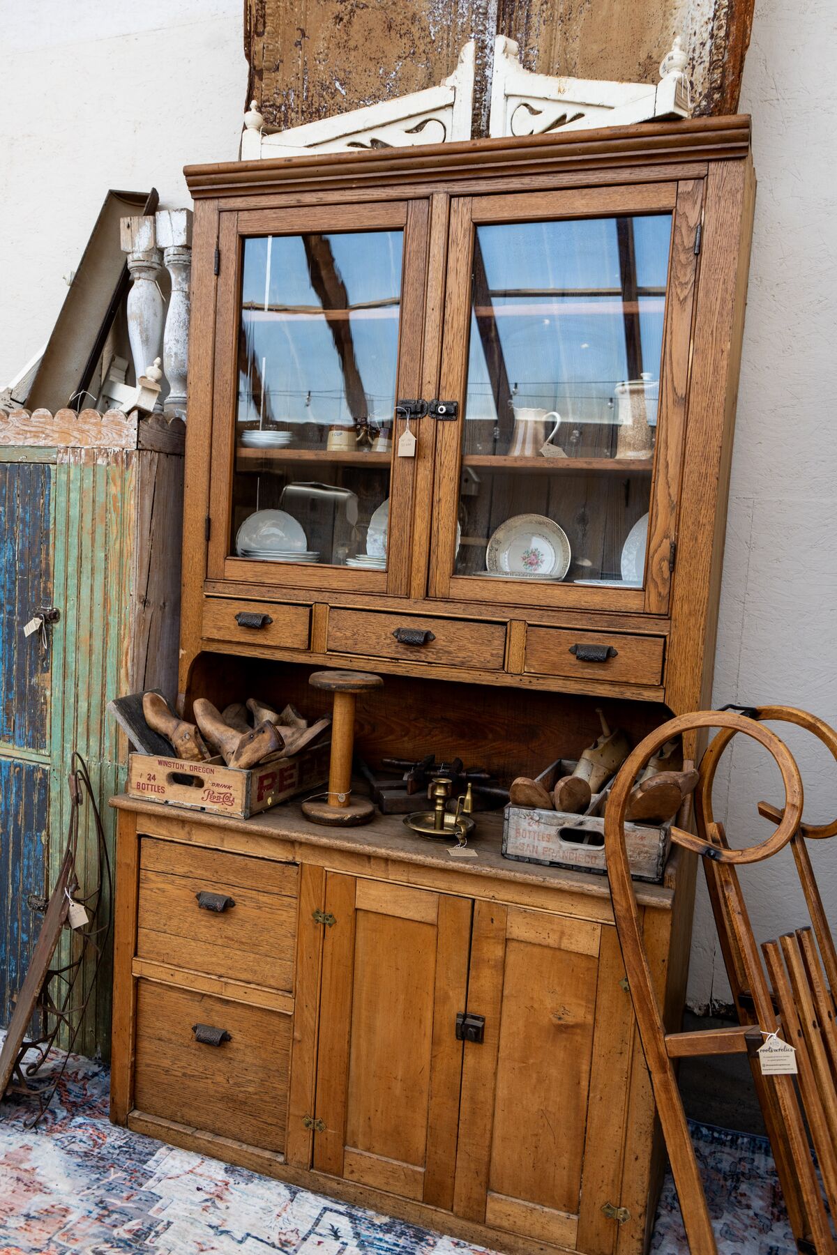 A pine dresser and glass-front cupboard arranged with ironstone and wooden pieces