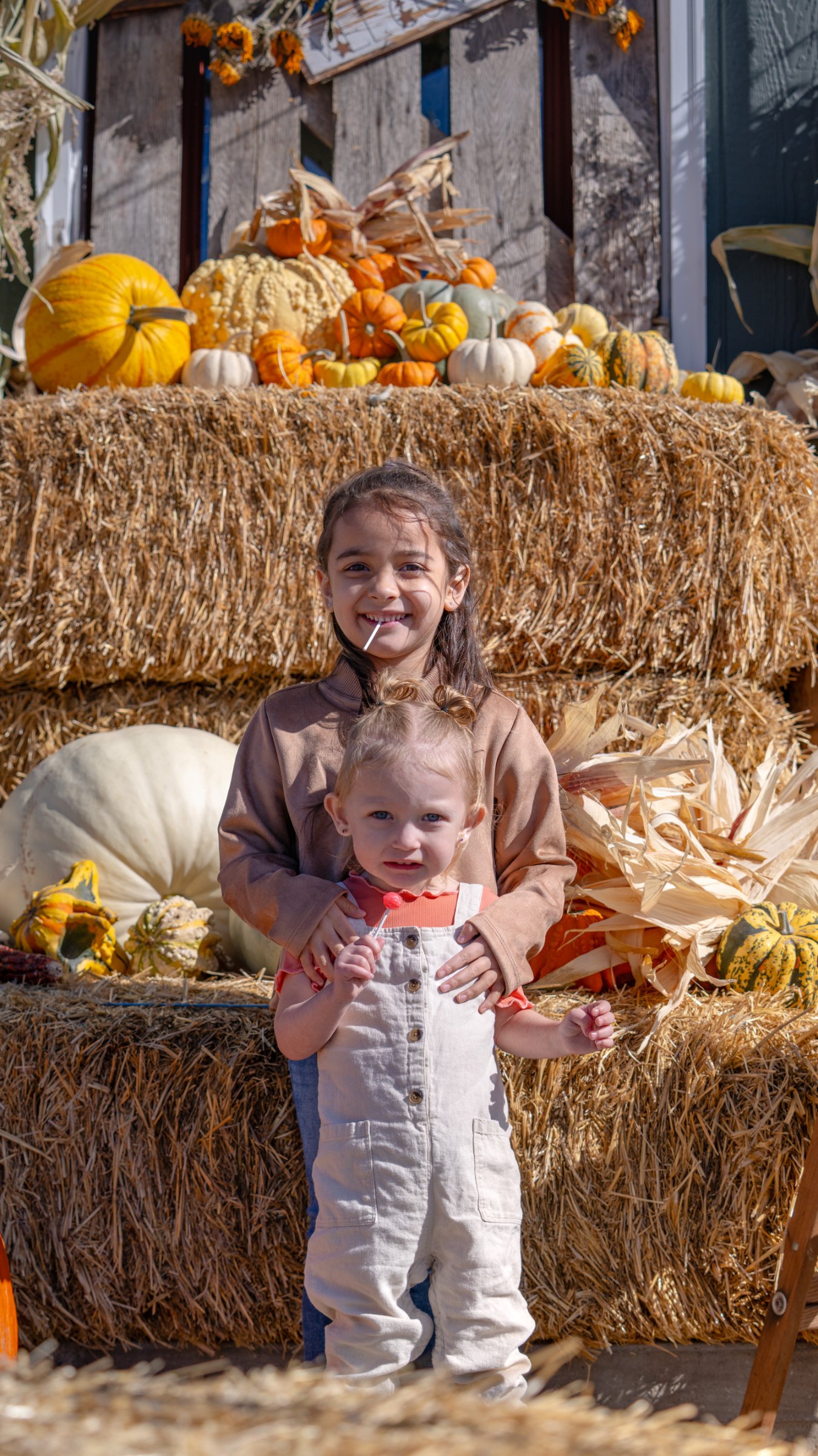 Children smiling in front of the outdoor autumn display
