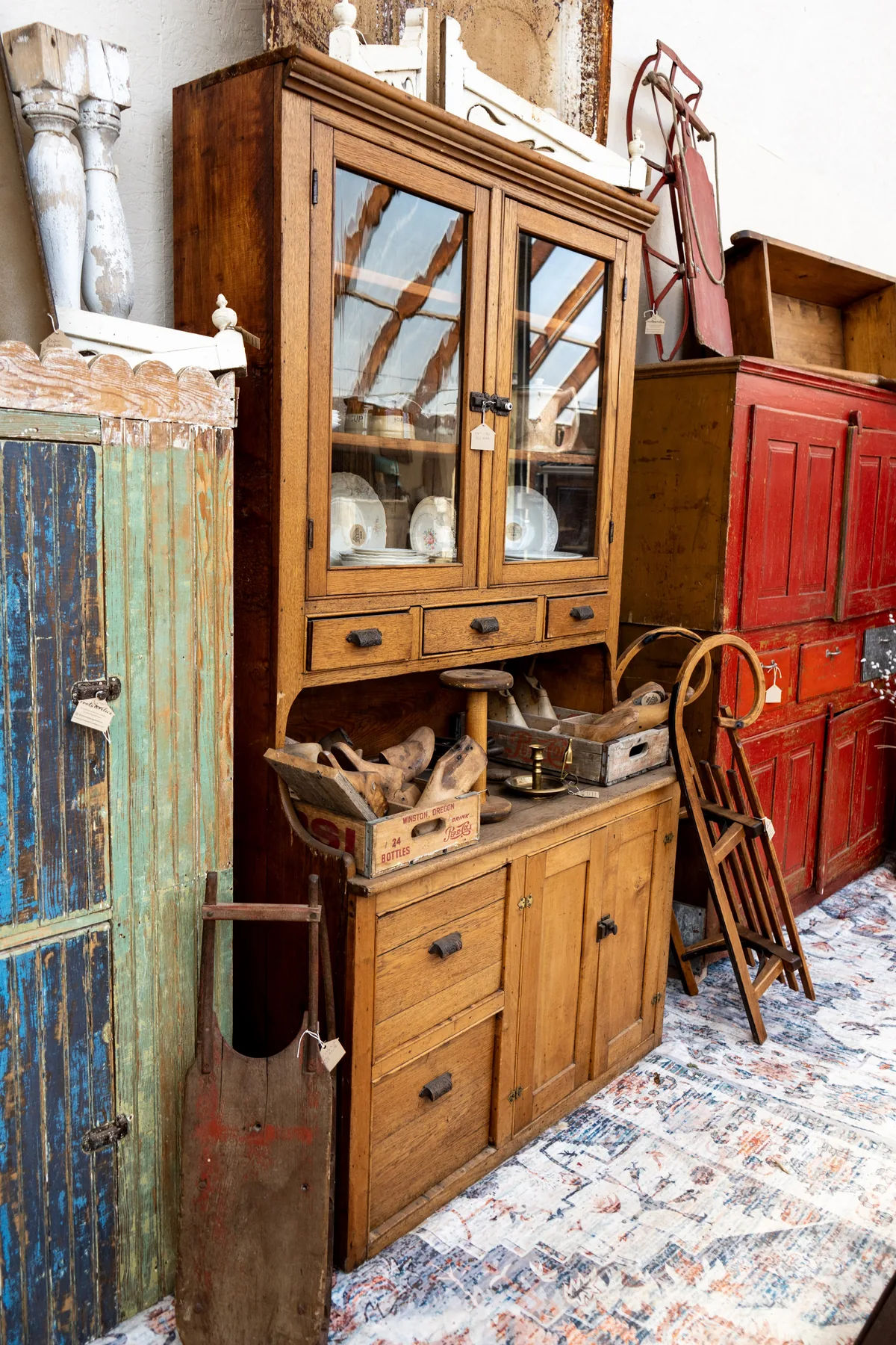 A close arrangement of antique cupboards, a glass-front cabinet, and collected wooden pieces