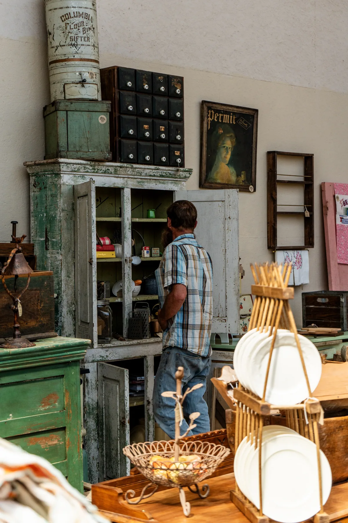 A guest browsing an antique green cabinet in the newly arranged greenhouse