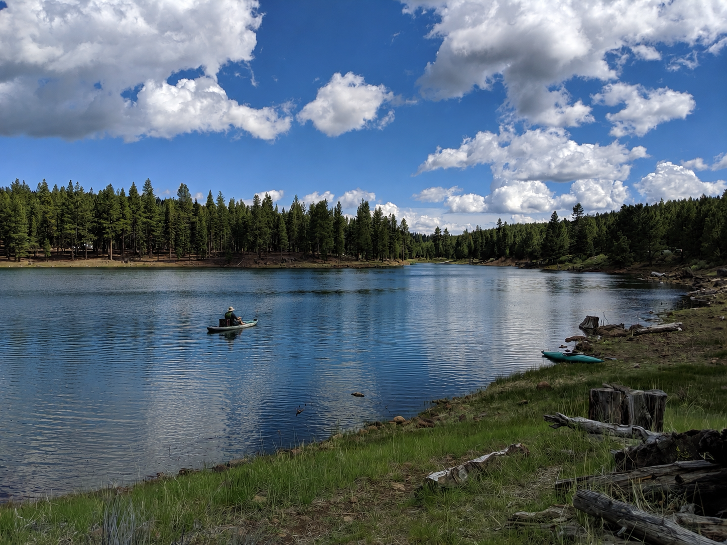 Kayaker crossing a mountain lake beneath summer clouds