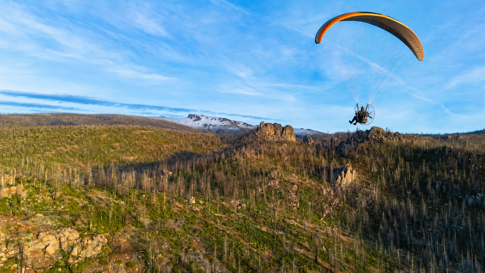 Powered paraglider flying over the mountains near Bly